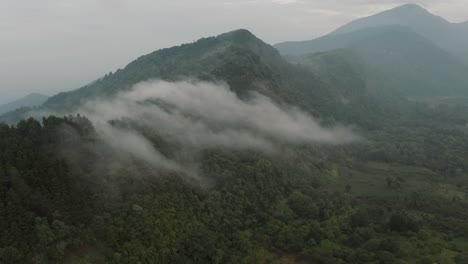 안개가 과테말라의 아티틀란 호수 근처의 숲이 우거진 산을 덮었습니다.