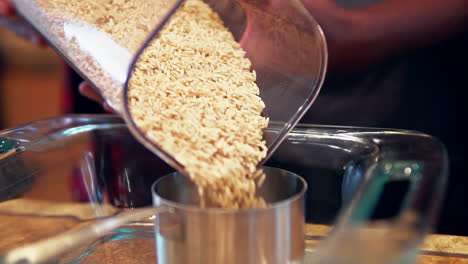 pouring whole grain brown rice into a measuring cup for a homemade recipe - slow motion