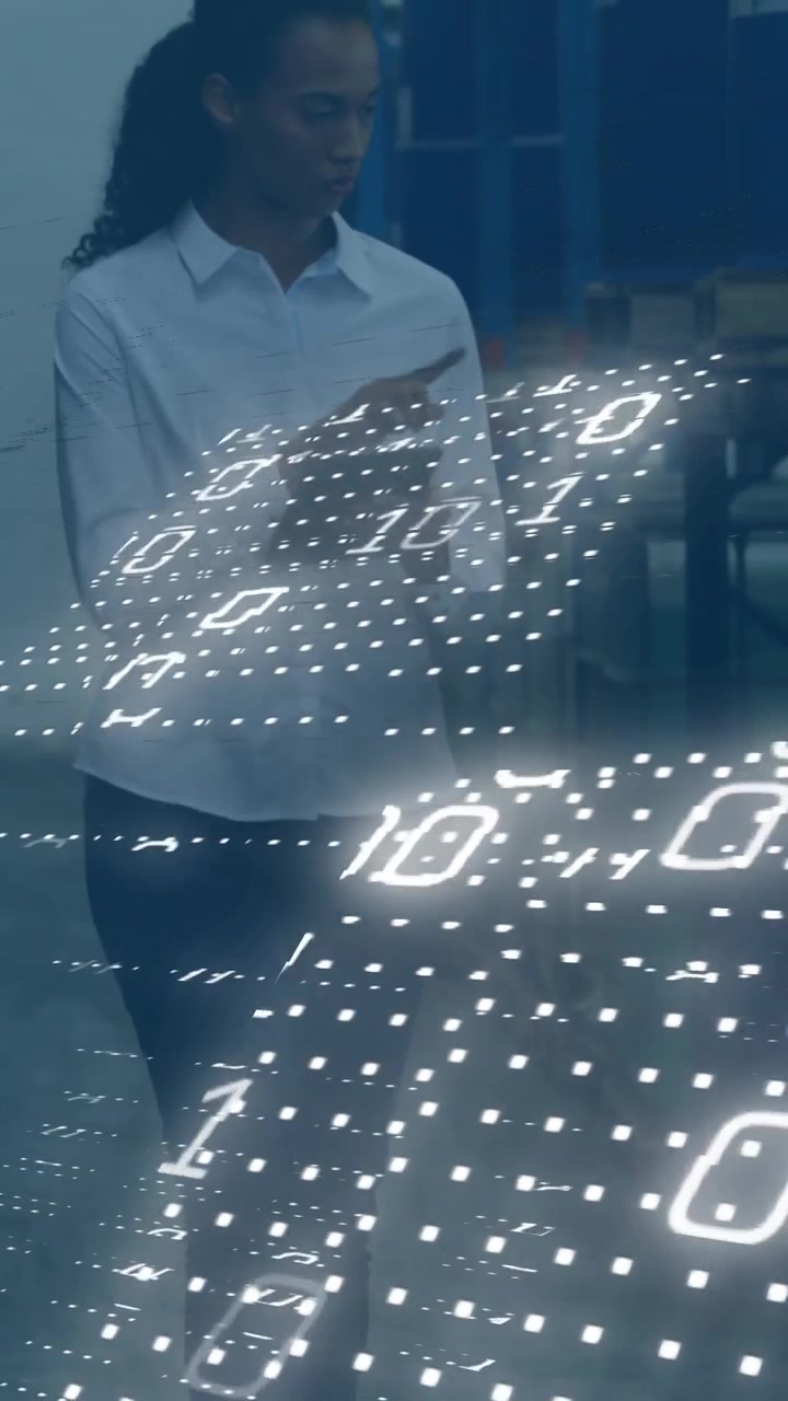 Vertical video: Warehouse tech walking aisle, tapping tablet activating binary grid across torso