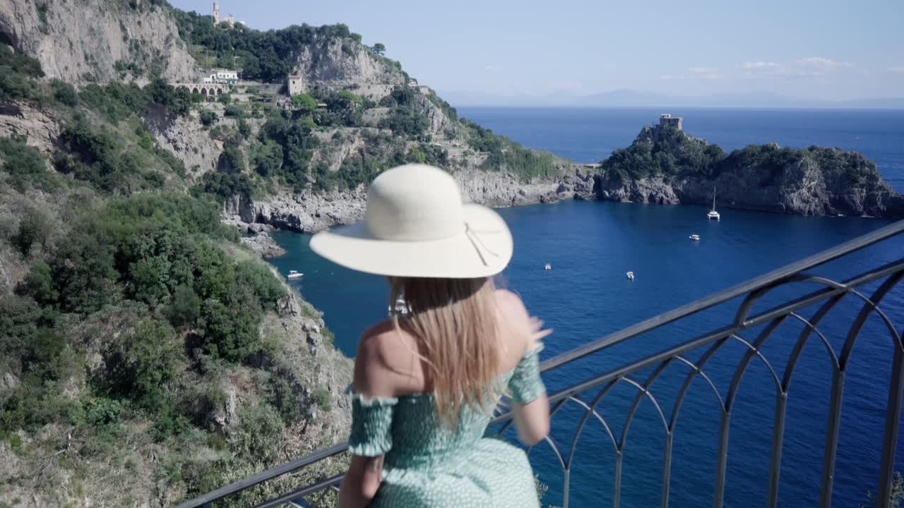 Beautiful Woman Walking Down The Stairs Overlooking Mediterranean Seascape And Rocky Cliffs In Conca dei Marini, Amalfi Coast, Italy