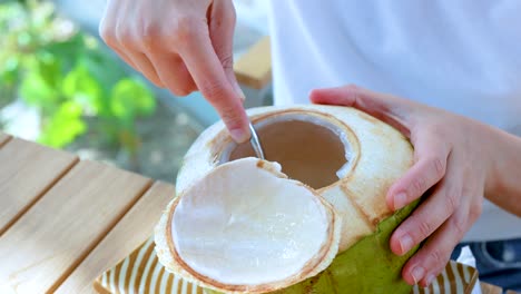 person scooping coconut meat with a spoon