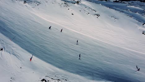 people skiing on white mountain slope in alps, aerial