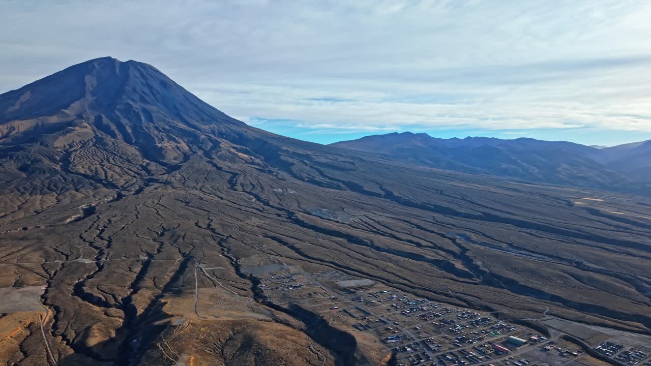 Vista aerea da drone del monte Misti in Perù che mostra ampie tracce di lava che si estendono attraverso il paesaggio, con la città di Arequipa sul bordo dell'inquadratura e il cielo blu sopra l'imponente vulcano