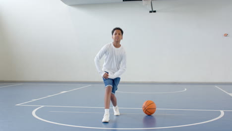 Practicing basketball moves, boy focused and determined on indoor court, copy space