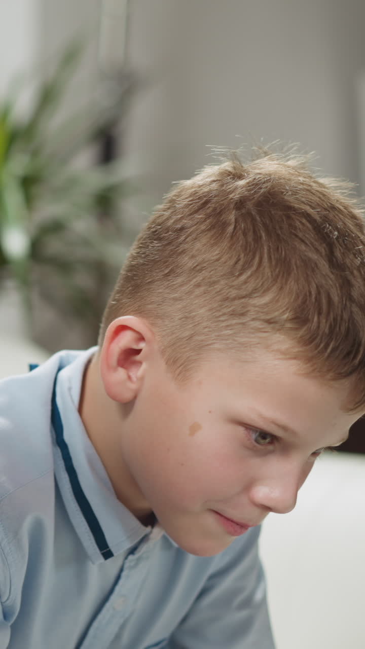 Young black man tutor conducts private English lesson to primary schoolboy at homeschooling with native speaker in living room closeup slow motion