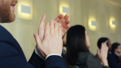 close-up de mãos de empresário caucasiano batendo palmas entre o público em uma sala de conferências