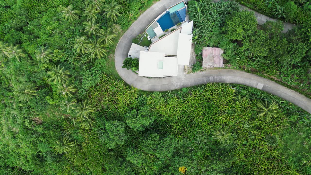 vista aérea de arriba hacia abajo de la carretera serpentina y las casas en el bosque tropical de baras, isla de catanduanes
