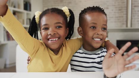 happy african american sister and brother making video call at home, slow motion