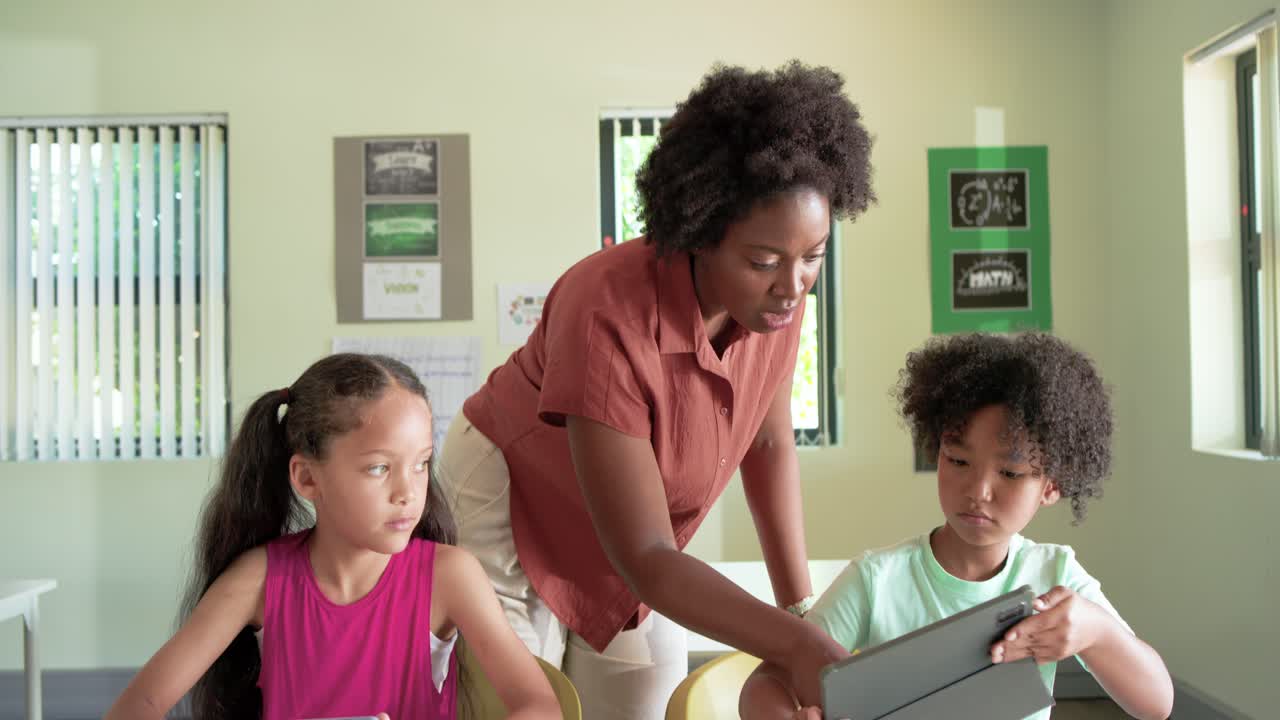 Teacher with students, noticing screens, leaning and adjusting tablet, guiding learning in class