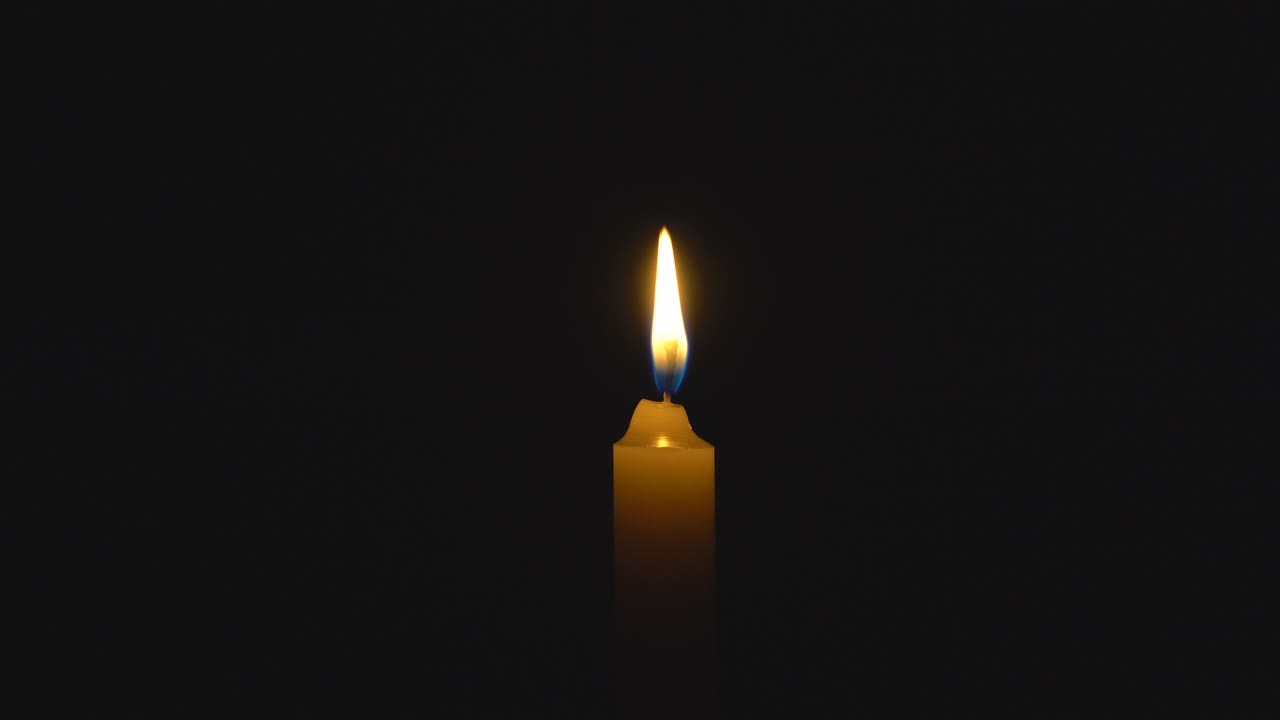 Una singola candela bianca che brucia. In loop per l'uso come sfondo o illustrazione di ricordo o celebrazione. Il vento cerca di spegnere la fiamma, ma essa si riprende ogni volta. La fiamma eterna