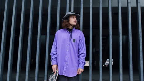 young stylish man staying outdoor. skater waiting for workout with longboard.