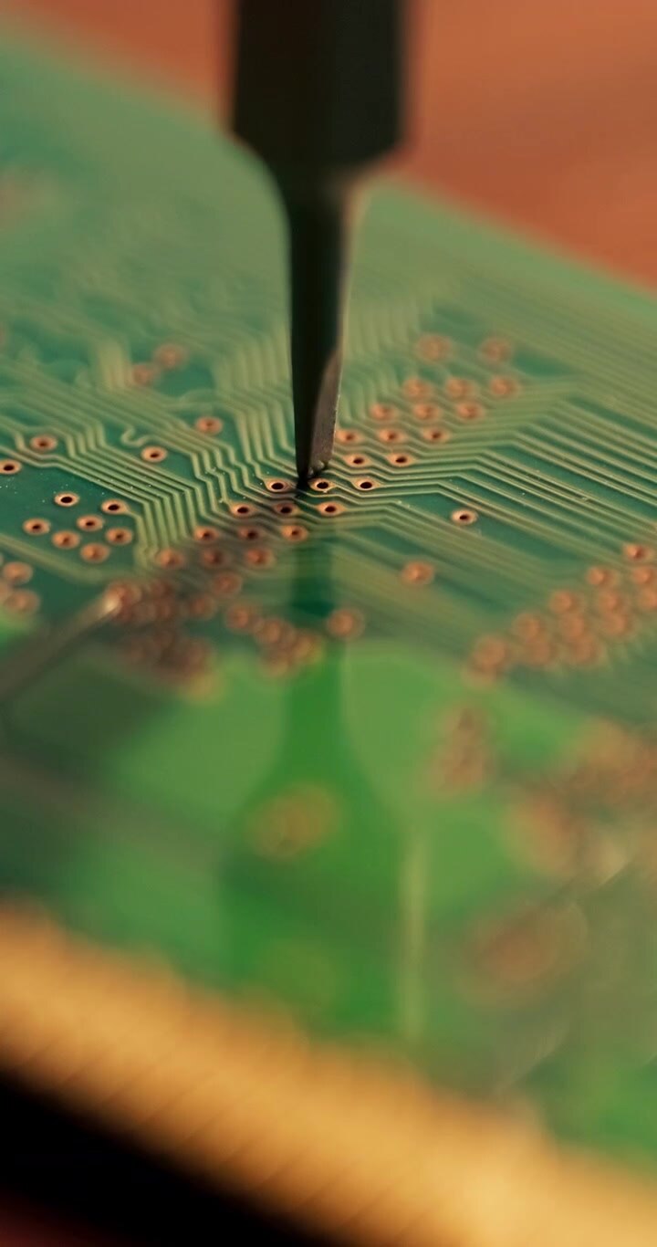 Vertikalt makrobillede af et værktøj, der graverer indviklede mønstre på et grønt printkort, hvilket fremhæver præcisionen i elektronisk fremstilling. Ideel til indhold på sociale medier inden for teknologi eller ingeniørvidenskab.