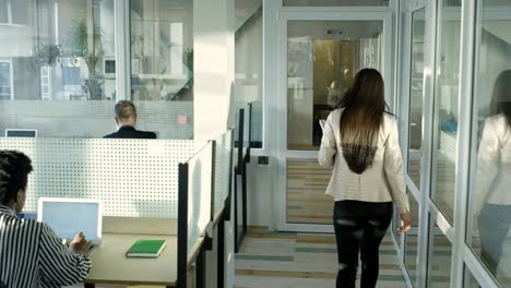 woman going through modern open space office with glass walls