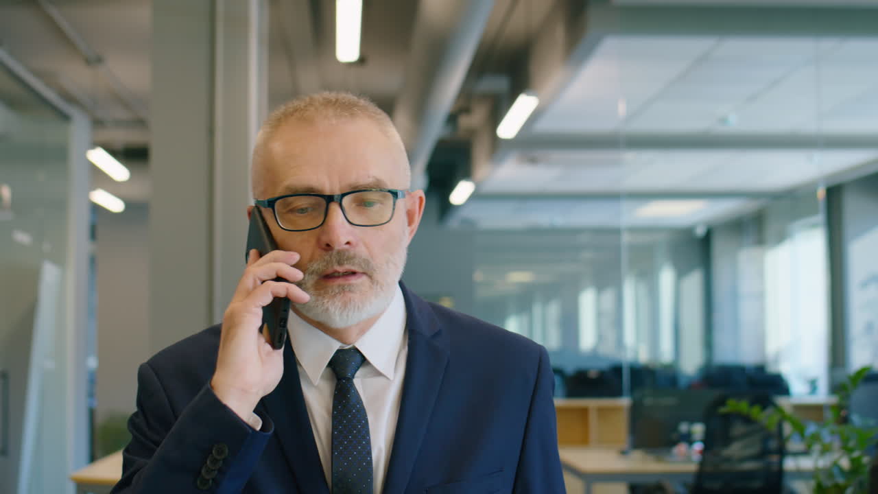 Senior Businessman Walking in Office and Speaking on Phone