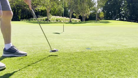 golfer focuses on putting under clear skies