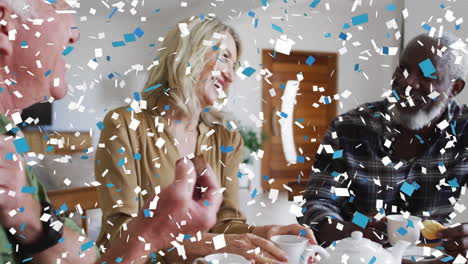 confetti falling against group of senior people smiling while having coffee together at home