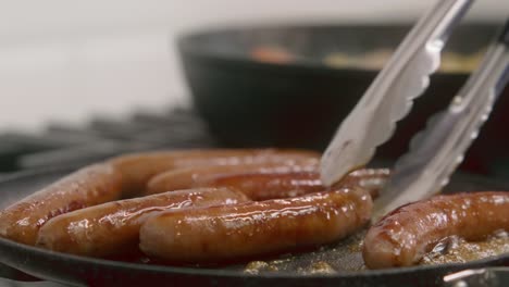 breakfast sausages are gently flipped as they cook in a cast iron skillet