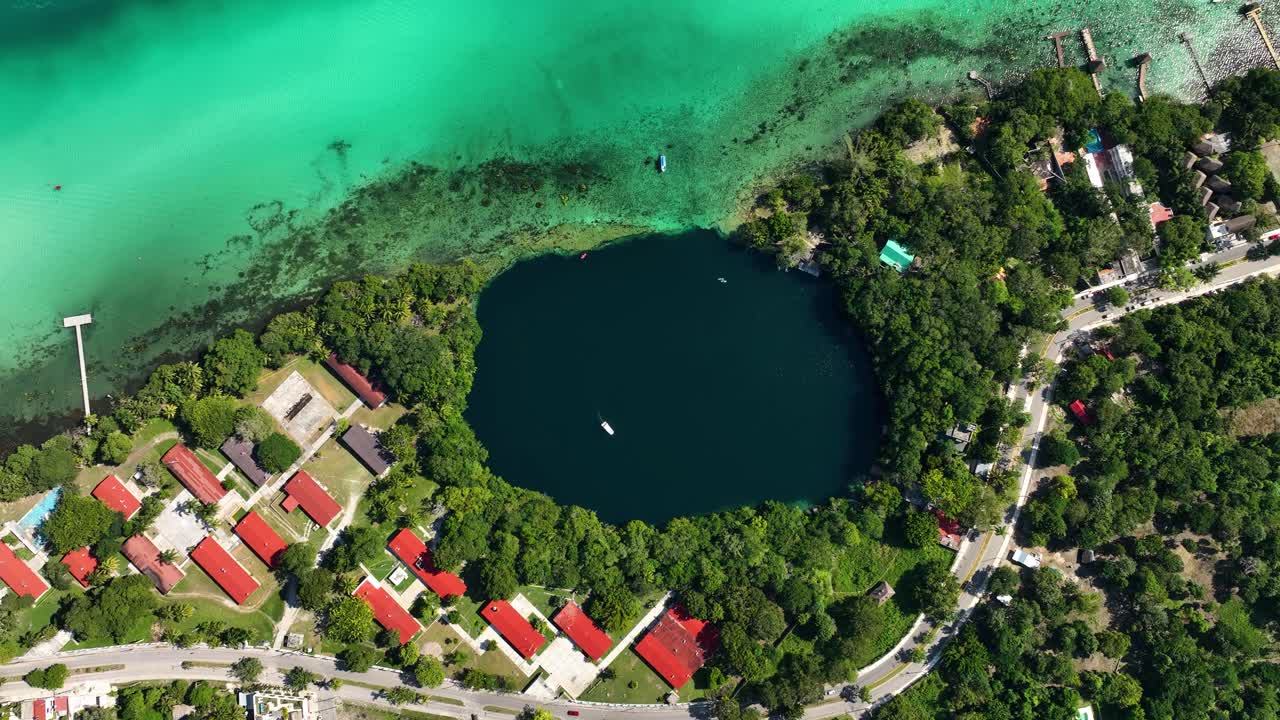 vista aérea sobre el cenote negro en la ciudad de bacalar, soleado méxico - de arriba hacia abajo, disparo de drones