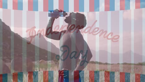 animation of independence day text over african american man drinking water in mountains