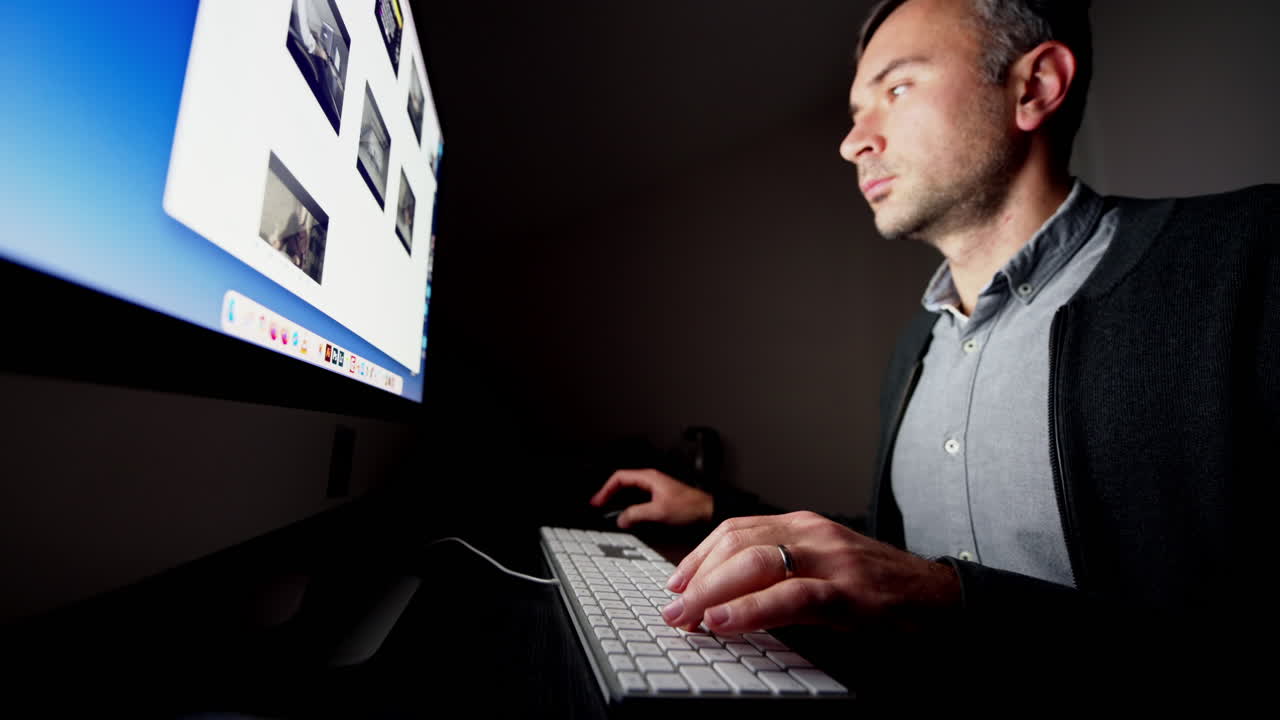 CHISINAU, MOLDOVA - NOVEMBER, 2021: Man working on iMac computer at night, dark room