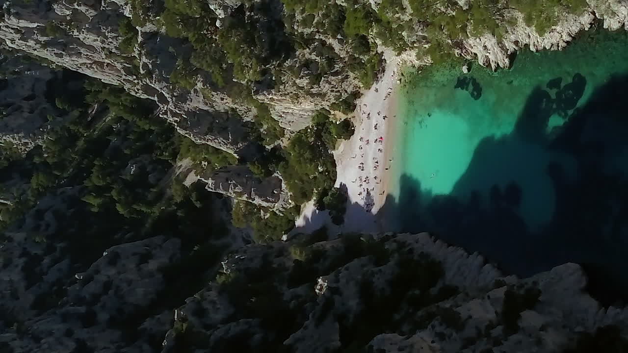 Den lille, afsidesliggende, skjulte Calanque d'En-Vau strand indlejret mellem klipper nær Cassis, Frankrig - opstigende vertikalt luftfoto.