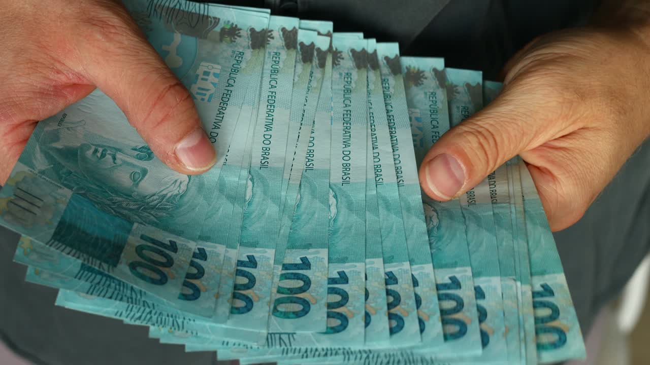 contando dinero brasileño, muchos billetes de cien reales, de cerca. concepto financiero