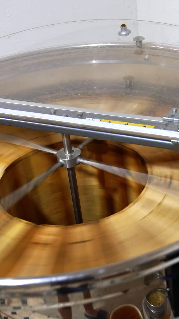 Metal barrel machine for honey extraction. Electric centrifuge spinning and rotating frames inside. View from top. Vertical video