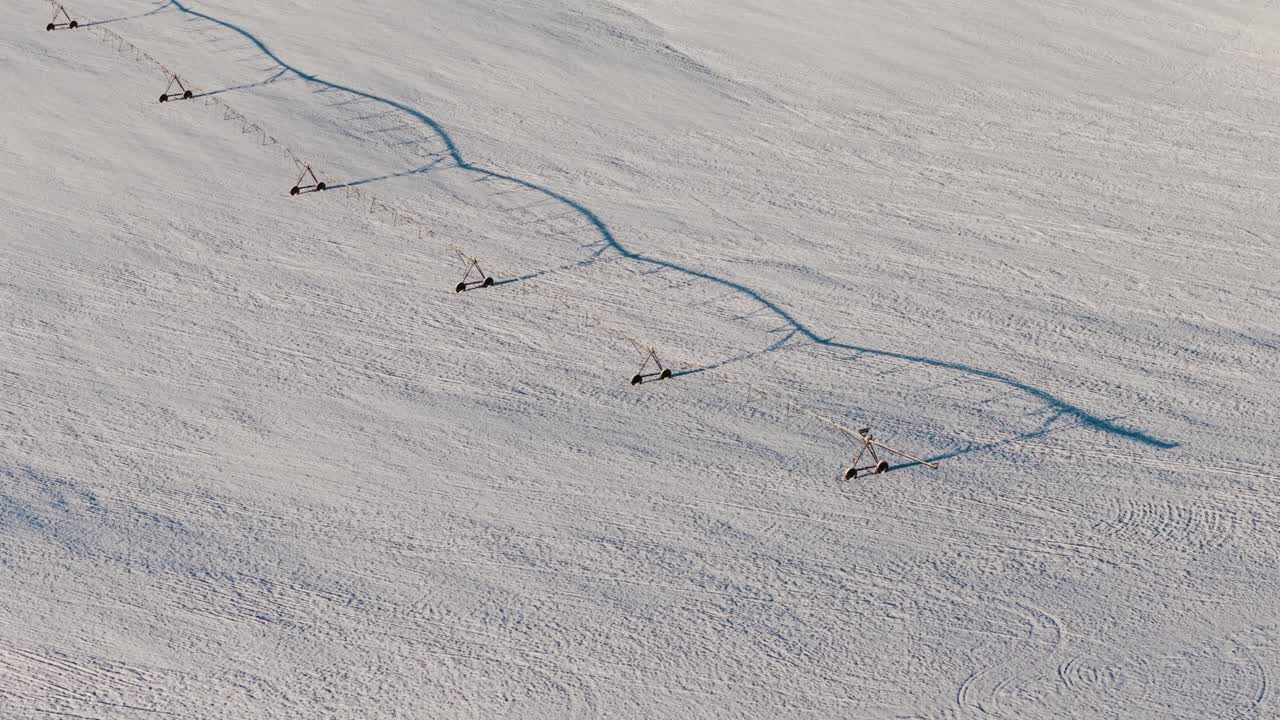 A drone close-up view of a pivot irrigation system stretching across a snow-blanketed field in South Georgia, captured during a rare snowfall event.