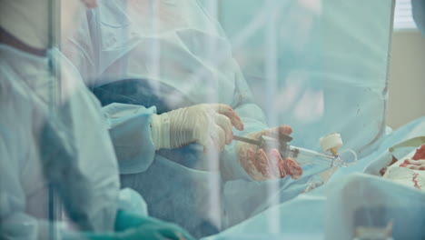 Outside-view-of-an-operating-room,-two-surgeons-operate-on-a-patient-lying-on-hospital-bed