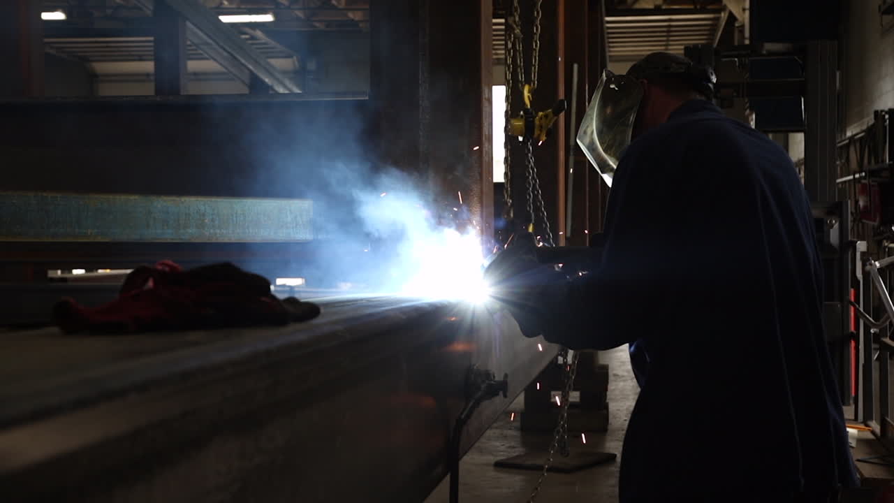 An industrial worker welding steel beams together