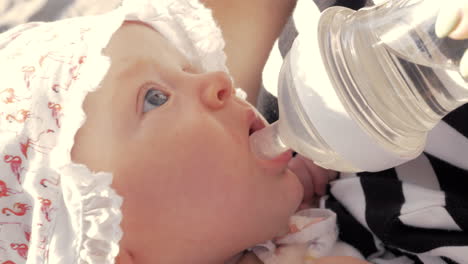 mother giving baby girl to drink from the bottle