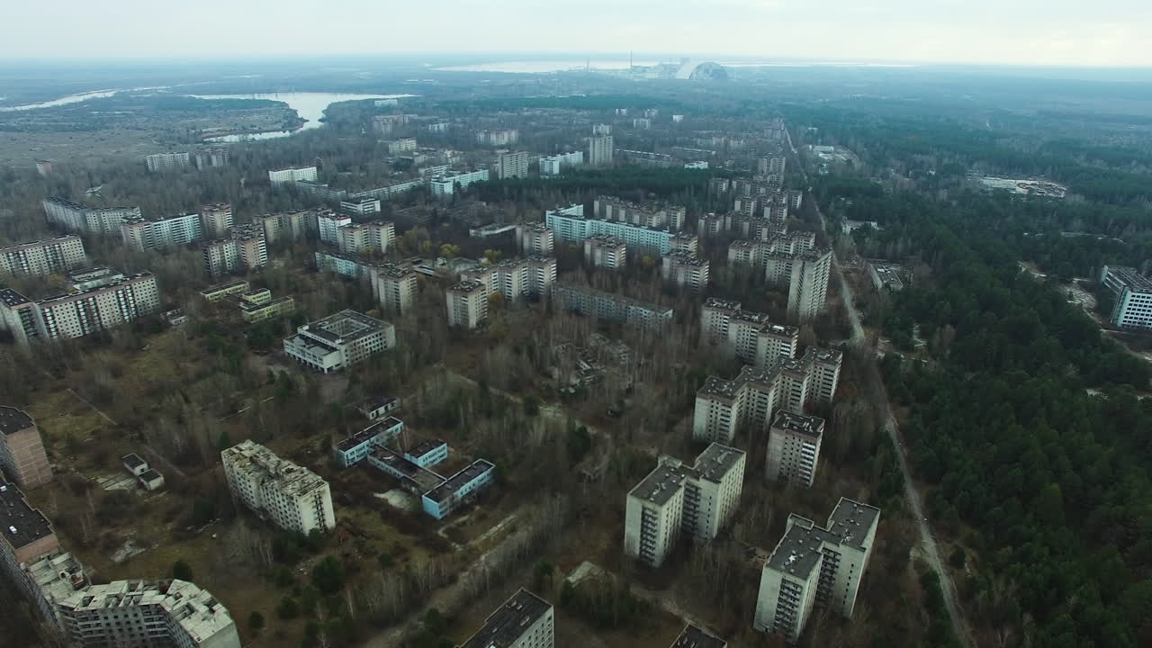 Vista aérea de Pripyat, uma cidade abandonada perto da Central Nuclear de Chernobyl. Blocos residenciais em ruínas, ruas tomadas pela vegetação, Novo Confinamento Seguro
