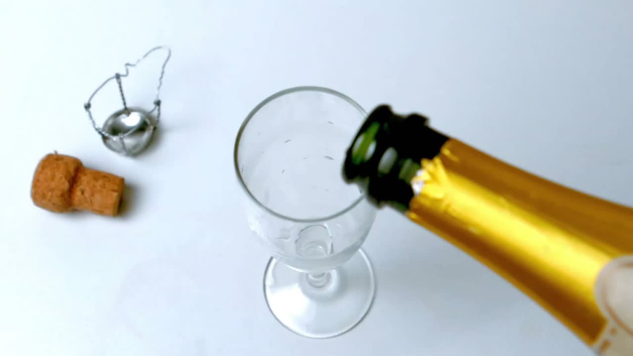 After cork popping, champagne bottle neck pouring into glass, hearts appearing, celebrating toast