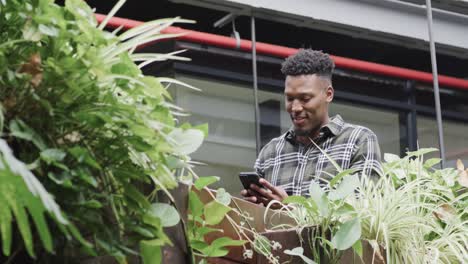 Happy-african-american-male-creative-using-smartphone-at-casual-office,-in-slow-motion