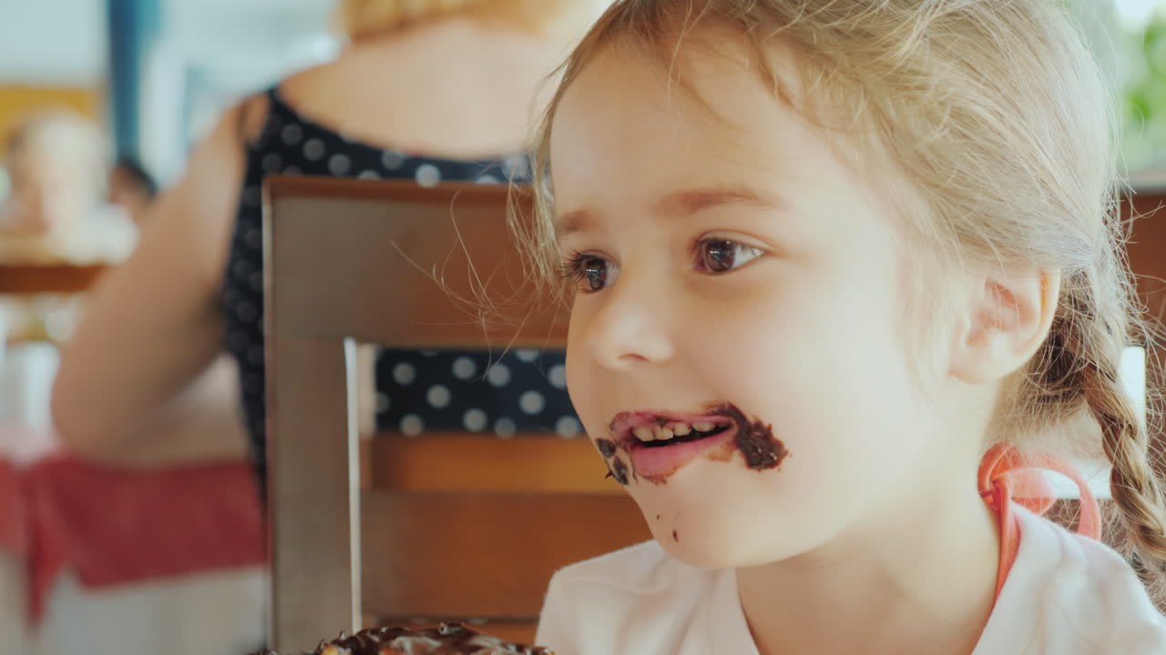una niña traviesa con la cara manchada de chocolate sonríe al retrato de la cámara