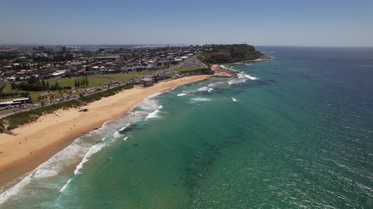 Surfers And Splashing Waves At Merewether Beach On Sunny Day In Newcastle, NSW, Australia. aerial descend
