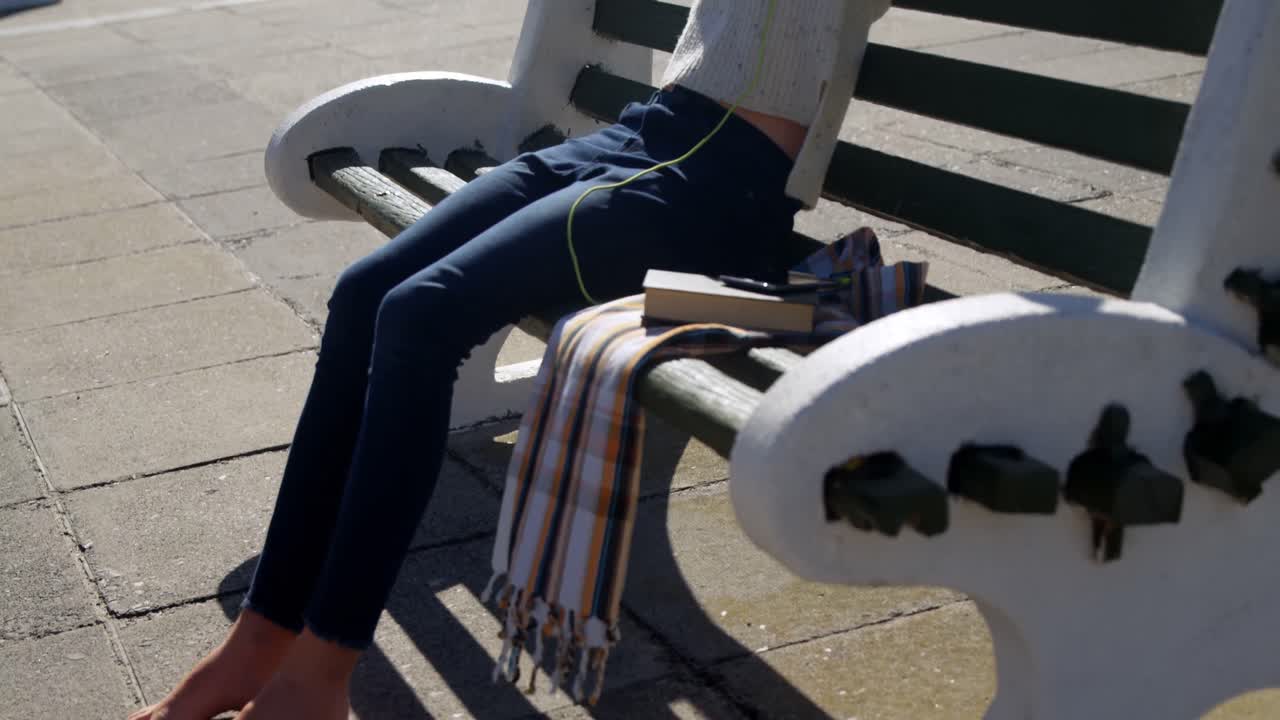 해변 4k에서 헤드폰으로 음악을 듣는 소녀