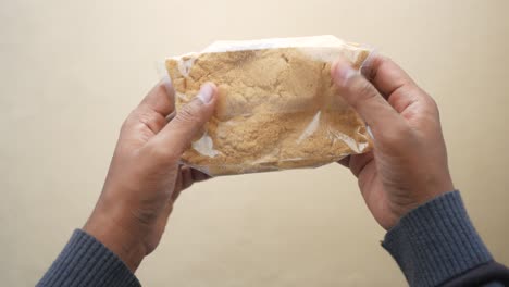 manos sosteniendo un paquete de polvo marrón