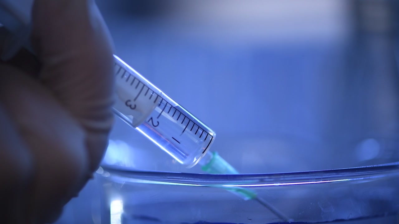 Siringa medica che aspira liquido trasparente in un laboratorio scientifico