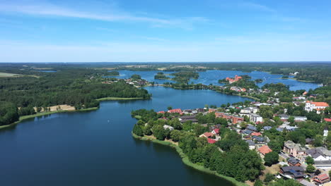 aerial: flying backwards and revealing majestic view of trakai town with blue color lake and forest in the background