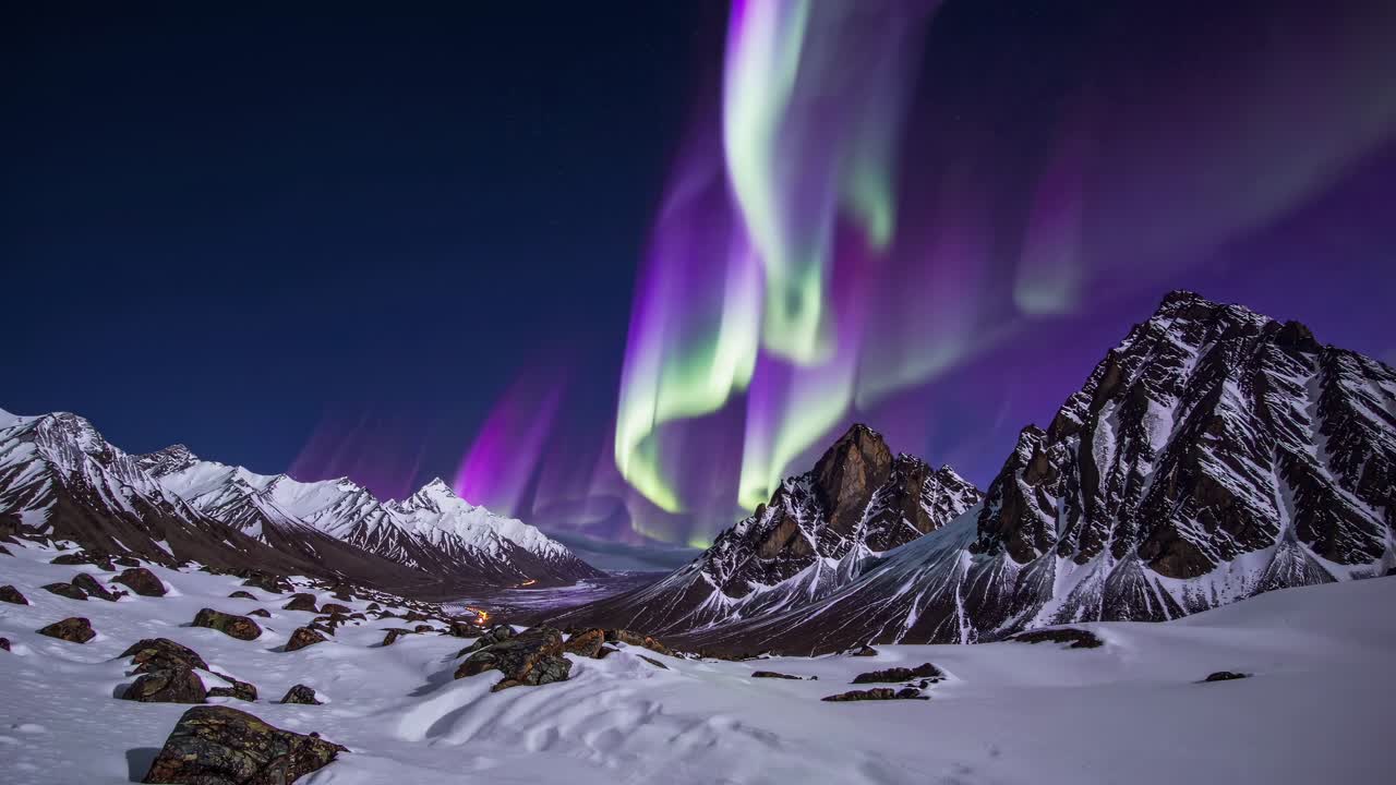 A mesmerizing wide-angle video shot of the Northern Lights over snow-capped mountains