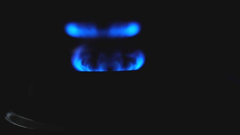 blue flame of gas stove on black background. gas switching on.