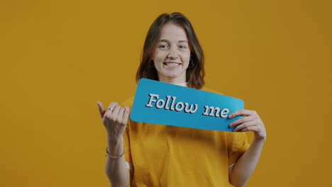 young woman holding a 'follow me' sign