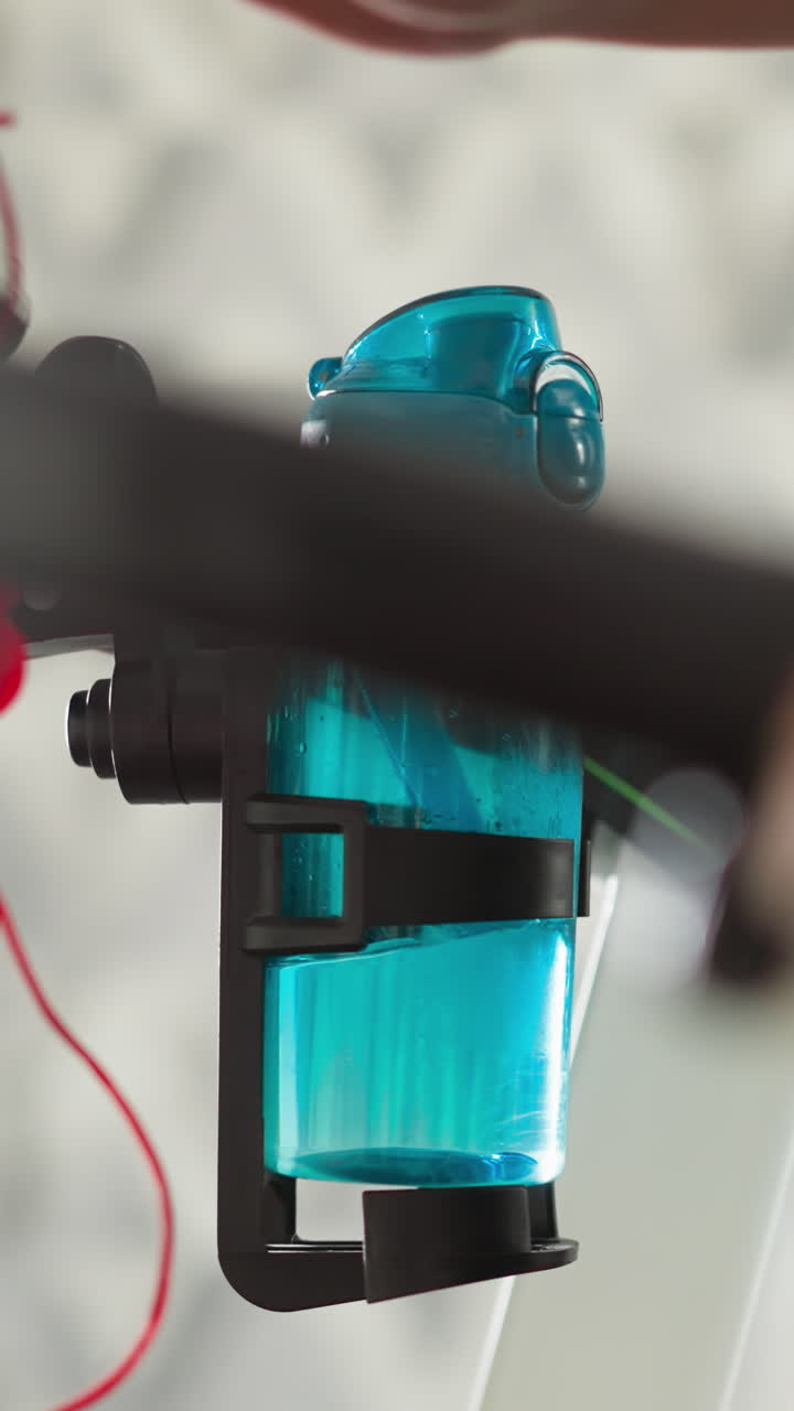 una mujer coloca una botella en el soporte de un dispositivo de ejercicio en primer plano. una mujer deportiva en forma prepara una bebida rejuvenecedora para un riguroso entrenamiento de jogging en un apartamento