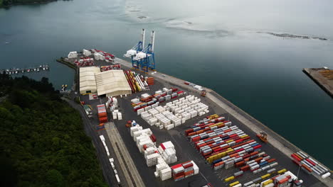 cargo containers and cranes in port of dunedin city, new zealand, aerial view