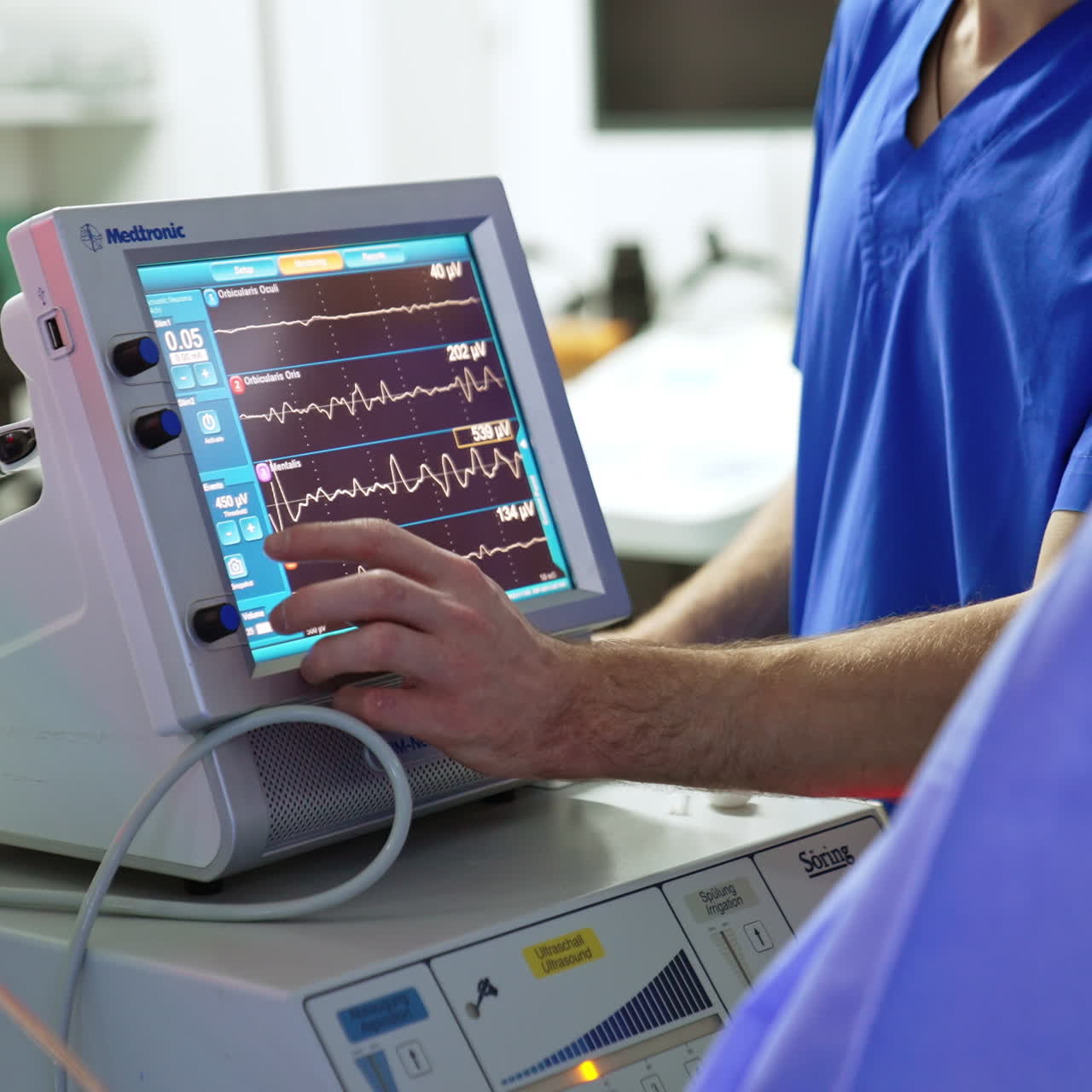 Unrecognized male medic in blue uniform stands near the lung ventilating machine. Surgery room equipment working at operation.