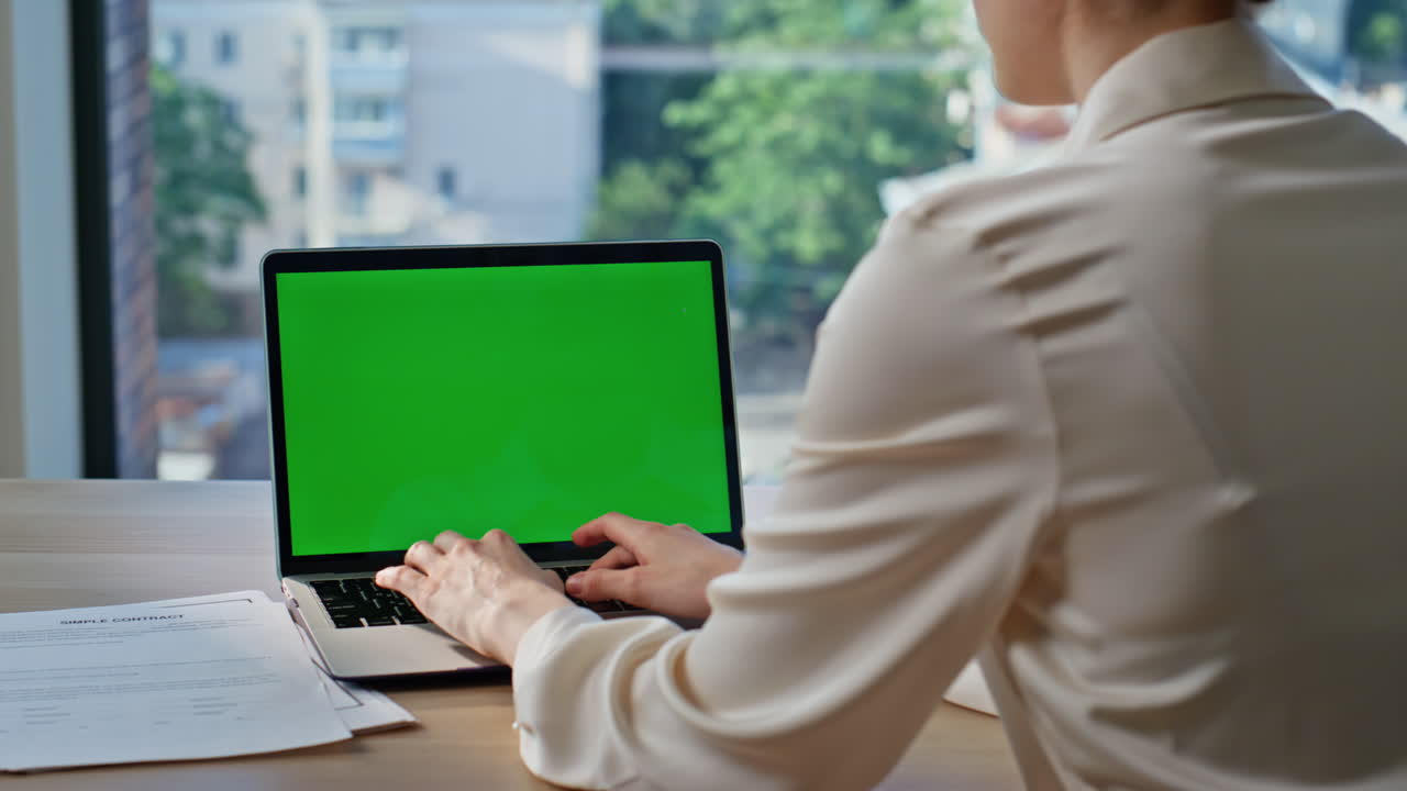 Woman typing chroma key laptop at office window closeup. Unknown businesswoman