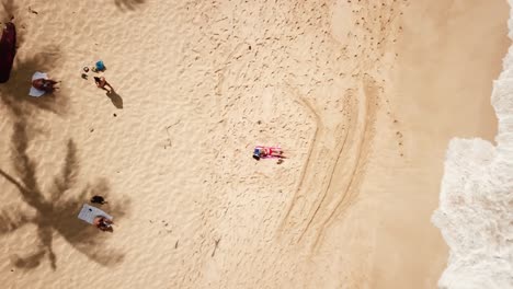 Toma-Aérea-Ascendente-Sobre-Una-Mujer-En-Bikini-Rojo-Relajándose-En-Una-Playa-De-Arena-Tropical-En-Hawaii