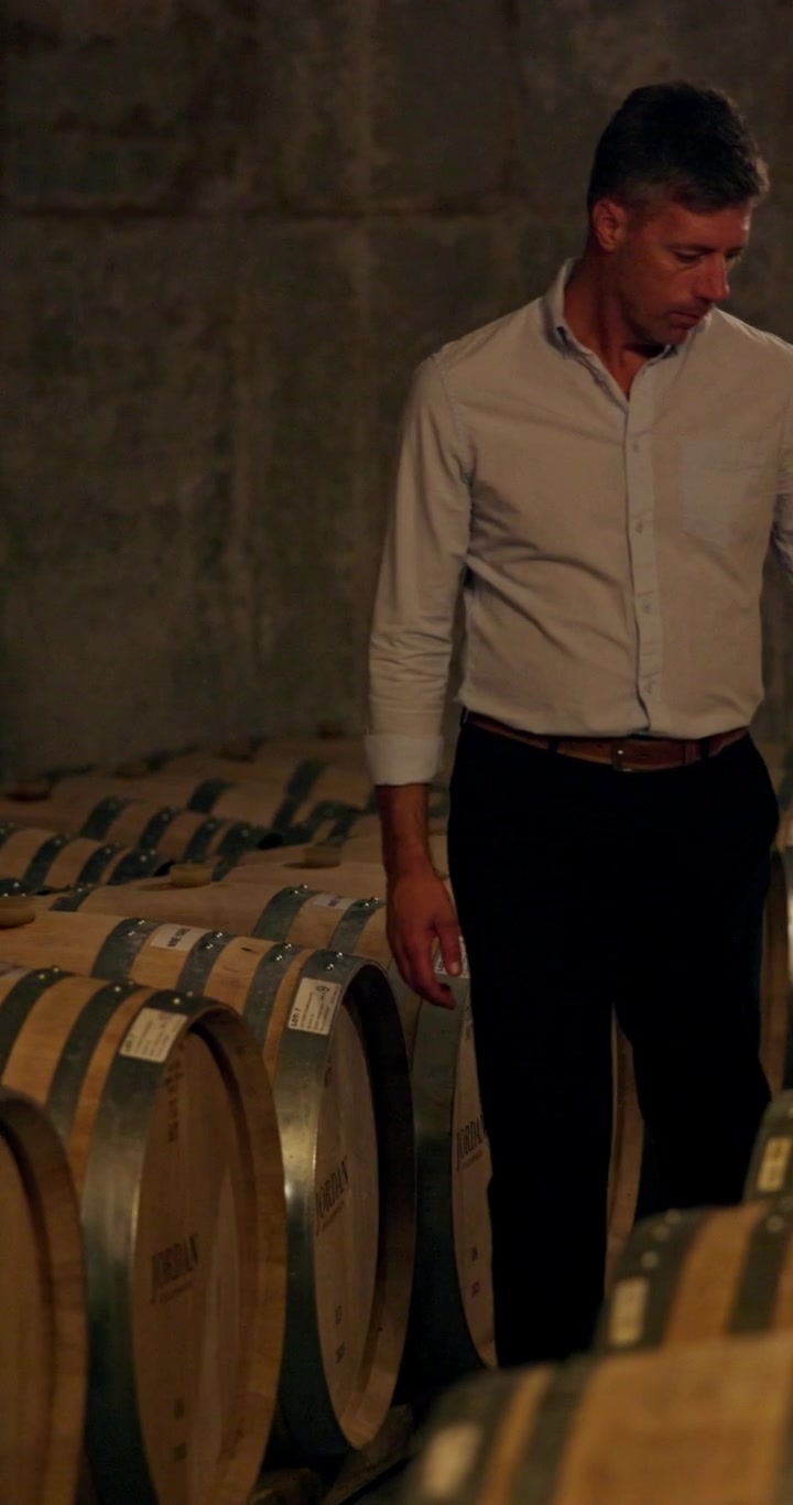 Viticoltore che ispeziona le botti di rovere in cantina