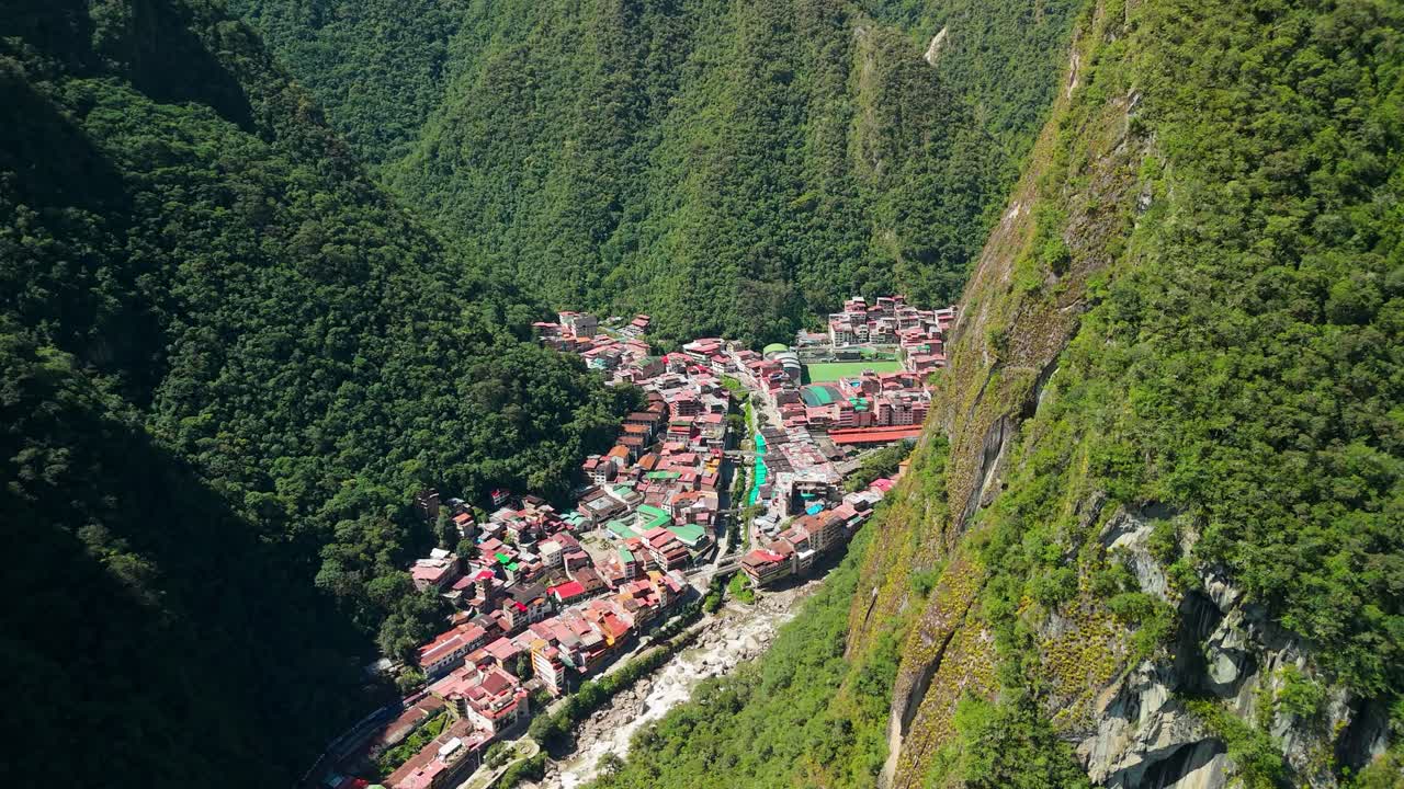 High drone overview of Aguas Calientes nestled in steep Andean terrain surrounded by lush vegetation